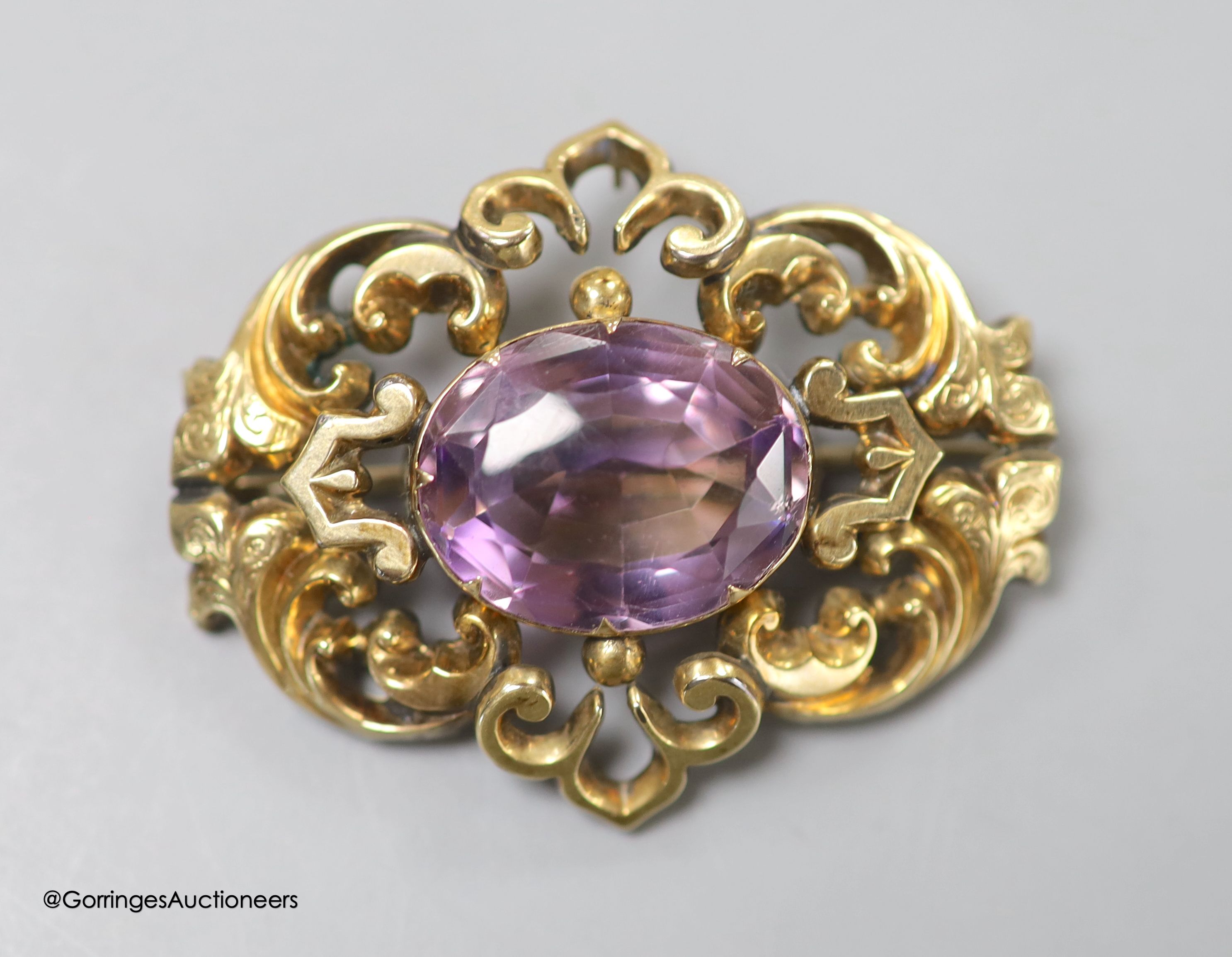 A cased late Victorian yellow metal and amethyst set pierced scroll brooch, 45mm